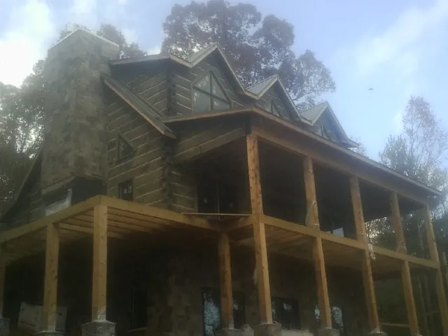 Stone chimney and dormers on a large log home with a timber porch in Strasburg